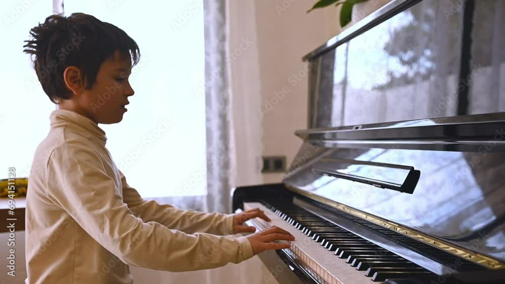 Handsome teenage boy, pianist playing grand piano, touching the black and white keys with his fingers to create the rhythm of the melody. People. Kids development and entertainment. Arts. Education