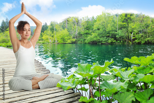 Woman meditating on wooden pier near river, space for text