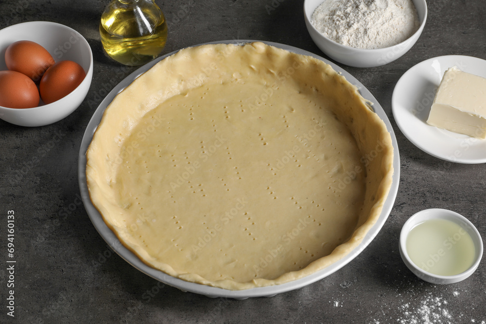 Quiche pan with fresh dough and ingredients on dark grey table, closeup Quiche pan with fresh dough and ingredients on dark grey table, closeup
