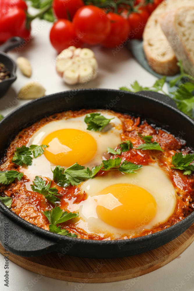 Delicious shakshuka in frying pan on white table, closeup Delicious shakshuka in frying pan on white table, closeup
