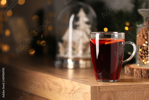 Delicious mulled wine in glass cup on wooden table. Space for text