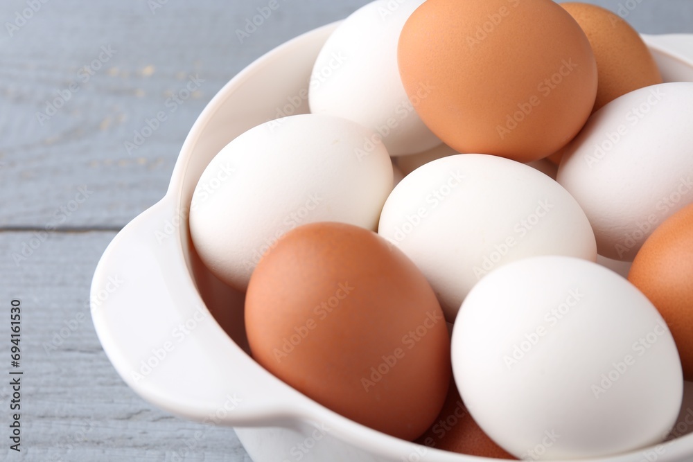 Unpeeled boiled eggs in saucepan on grey wooden table, closeup Unpeeled boiled eggs in saucepan on grey wooden table, closeup