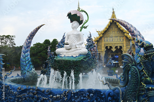 Phra Upakut is a pearl white statue placed in the middle of a fountain under the shade of lotus flowers. In front of the chapel at Wat Rong Suea Ten temple. Located at Chaing Rai province in Thailand. photo