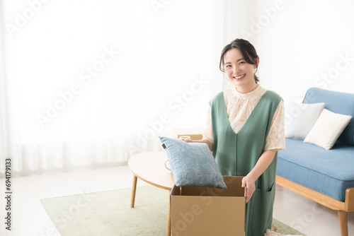 引っ越しの準備で段ボールに荷物を詰める笑顔の若い女性　カメラ目線