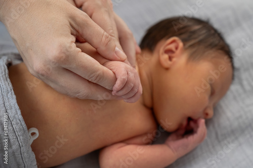 A newborn boy holds his mother's finger. Close-up of hands.