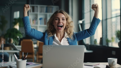 A young businesswoman in front of a laptop cheerfully celebrates success