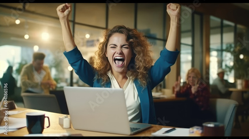 A young businesswoman in front of a laptop cheerfully celebrates success photo