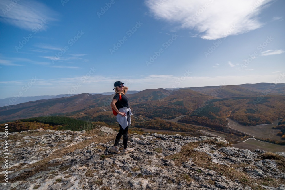 woman backpack on mountain peak looking in beautiful mountain valley in autumn. Landscape with sporty young woman, blu sky in fall. Hiking. Nature
