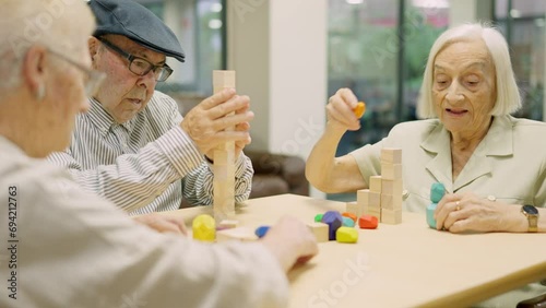 Concentrated seniors resolving brain skill games with wooden pieces in geriatric