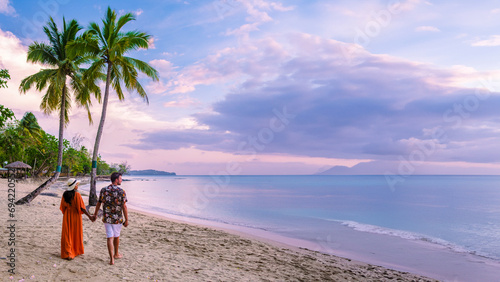 couple on the beach with palm trees watching the sunset at the tropical beach of Saint Lucia or St Lucia Caribbean Island. men and women on vacation in St Lucia a tropical island with palm trees photo