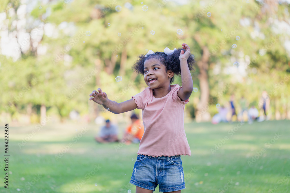 Happy kid girl playing with soap bubbles. Active child playing outdoors in the park Happy kid girl playing with soap bubbles. Active child playing outdoors in the park