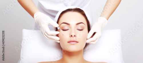Beauty woman receiving cosmetic injection in face on white background. Cosmetic procedure
