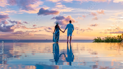 Young men and women watching the sunset with reflection in the infinity swimming pool at Saint Lucia Caribbean, couple at infinity pool during sunset in the evening light