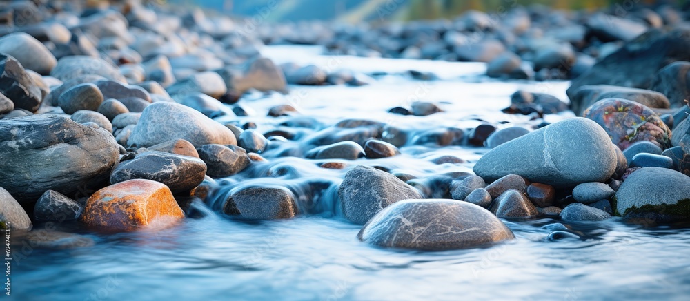 Motion-blurred water rapids flow over cobble stones in a closeup view. Motion-blurred water rapids flow over cobble stones in a closeup view.
