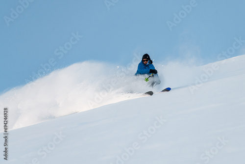 Skier is freeriding, downhill skiing, with powder rising up