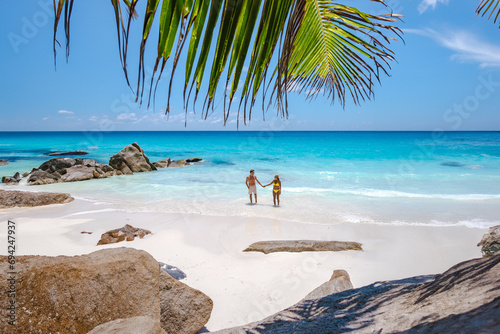 Fototapeta Naklejka Na Ścianę i Meble -  Anse Source d'Argent beach La Digue Island Seychelles, a couple of men and women walking at the beach at a luxury vacation. a couple swimming in the turqouse colored ocean