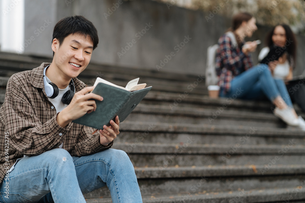 Obraz premium college student reading a book study on laptop prepare for the exam Or work on a group project while sitting on the steps of the university.