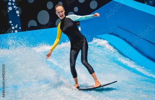 Photography Beautiful young woman surfing on a wave simulator at a water amusement park