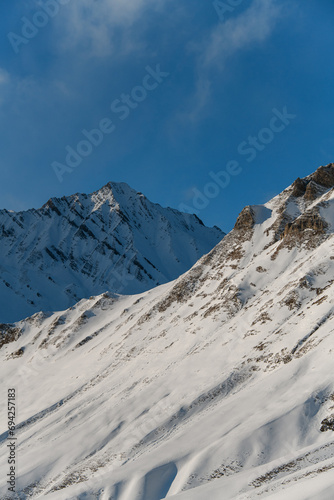 Snow-covered slopes merge with the blue clear sky