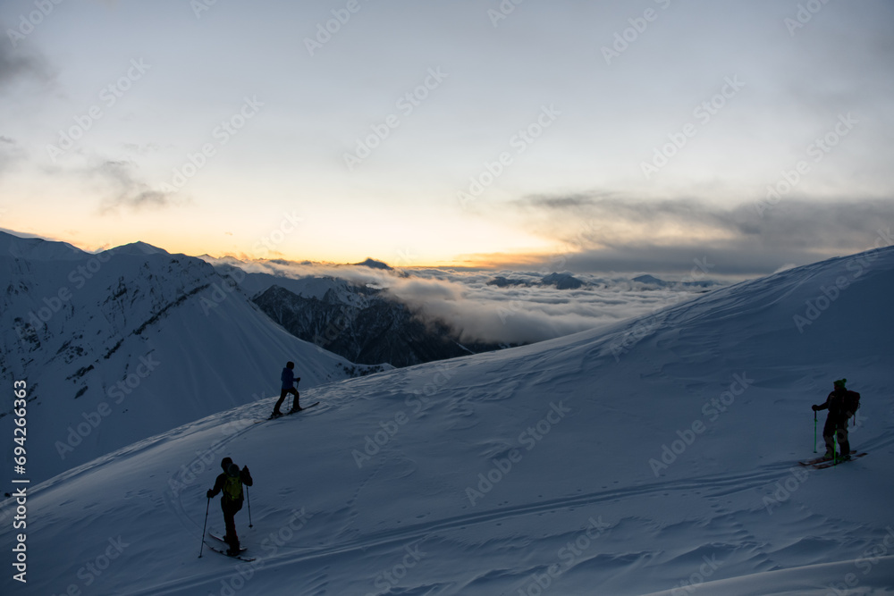 Three skiers are positioned on a mountain slope
