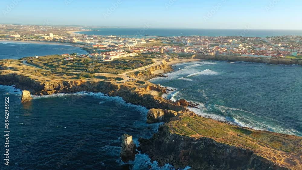 Drone approach and fly over Peniche, town, cliffs and sunset, Portugal