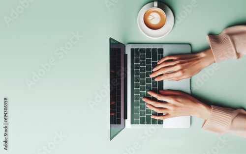 Top view of woman hands typing, using keyboard of laptop computer for online shopping, learning, design, email on a pastel green background desk at office. Copy space for text, advertising