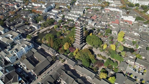 Drone aerial above Changshu City panning around the Suzhou Fangsi Pagoda surrounded by traditional Chinese buildings in sunny autumn day, 4k real time footage high angle view. photo