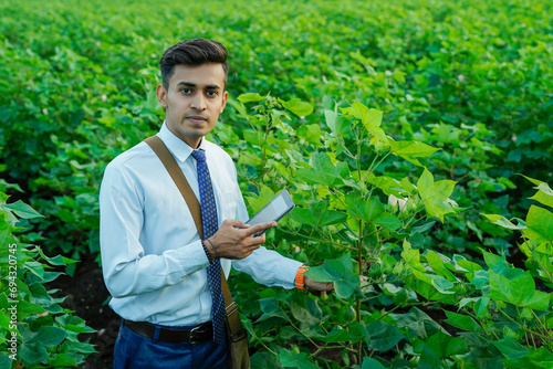 Indian agronomist or banker using tablet or phone at agriculture field.