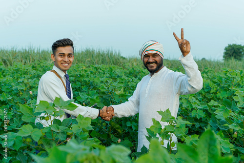Young indian agronomist or banker showing some information to farmer at agriculture field.