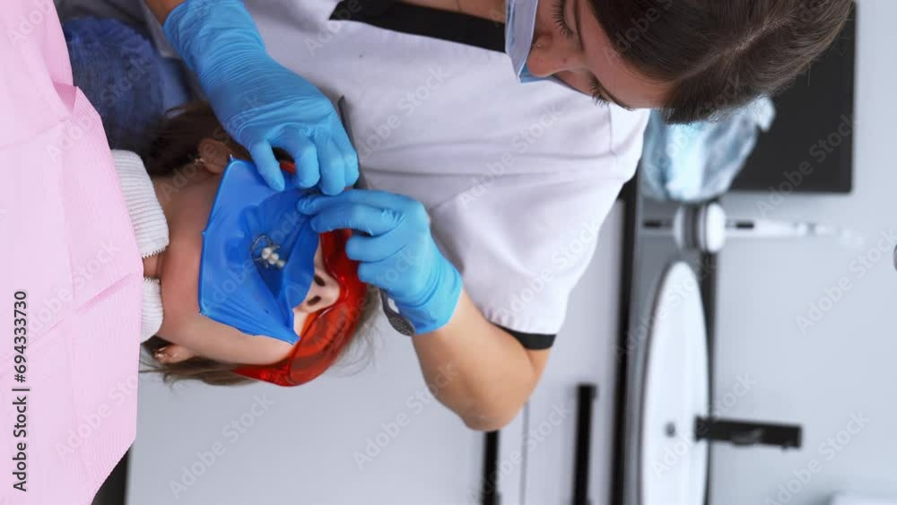 Dentist's hands in gloves with dental punch and cofferdam scarf