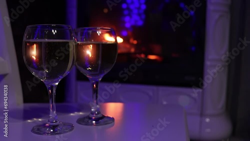 Closeup view of couple of champagne glasses nearby fire. Bubbles and fire reflections in wine glasses
