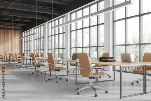 Cozy workspace interior with furniture, laptop on desk in row, panoramic window