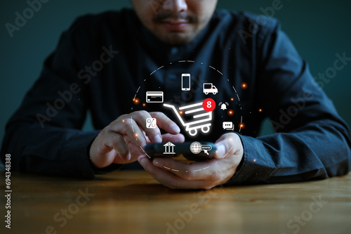 Man or customer using smartphone with shopping cart and business icon  Online shopping and e-commerce technology internet concept  shopping service on the online web and offers home delivery.