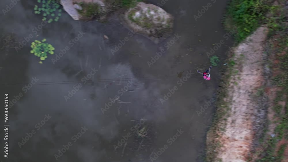 An adventurer travelling on a high-speed zip line rope above a lake amidst the jungle An adventurer travelling on a high-speed zip line rope above a lake amidst the jungle