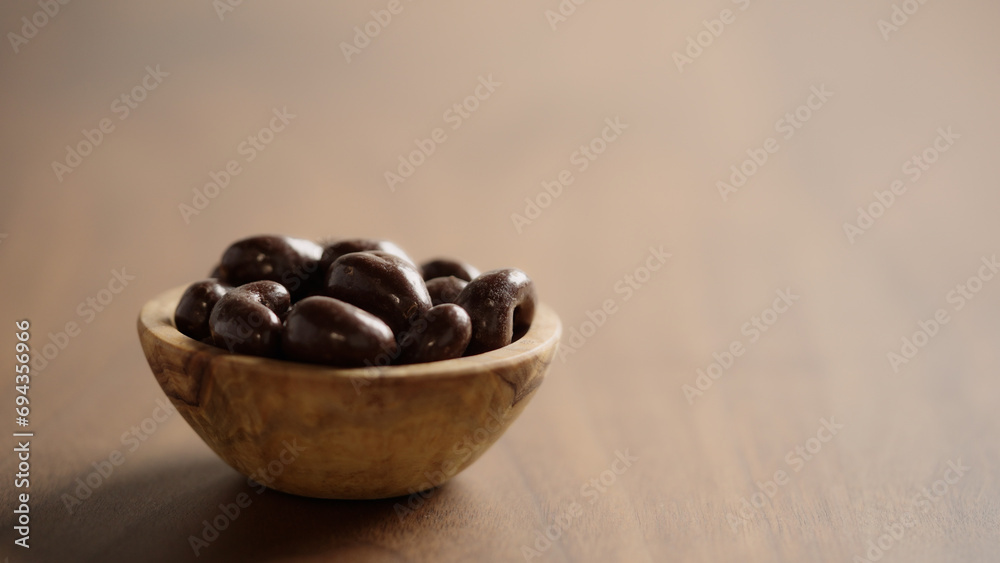 Obraz premium Chocolate covered cashew in a wood bowl closeup