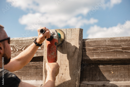 Man work on holiday repairing and renovating a country house - summer chores in the backyard and garden - power tool work