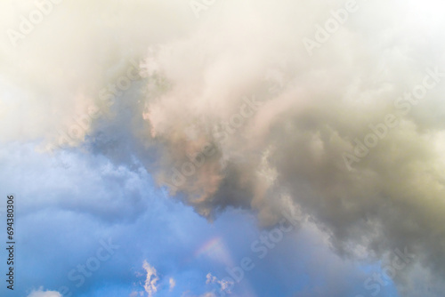 Background of summer cloudy sky with tiny rainbow