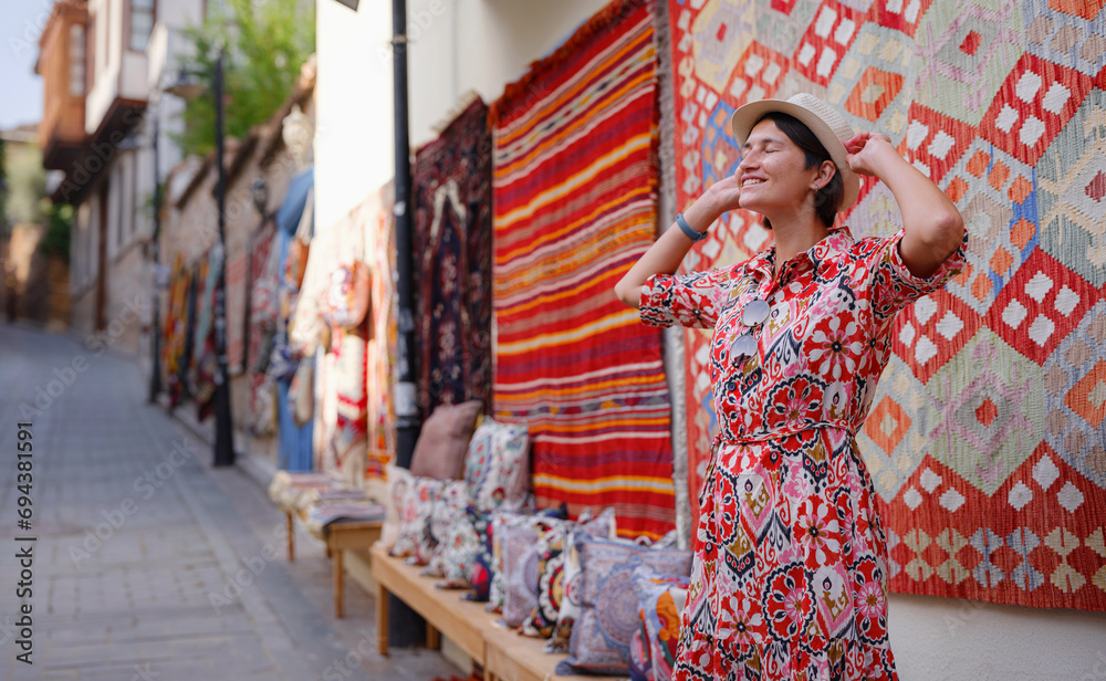 female summer travel to Antalya, Turkey. young asian woman in red dress walk through old town Kalechi , female tourist traveler discover interesting places and popular tourist traditional carpet