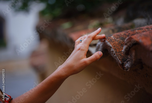 Female hand gently touches weathered tiles in old town of Kalechi, Antalya. tactile connection with ancient rooftops echoes rich history of surroundings photo