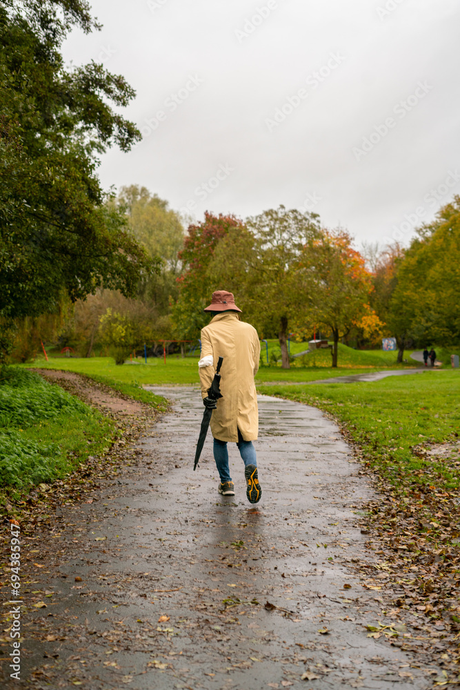 An adult man walking on the footpath in a public park in England
