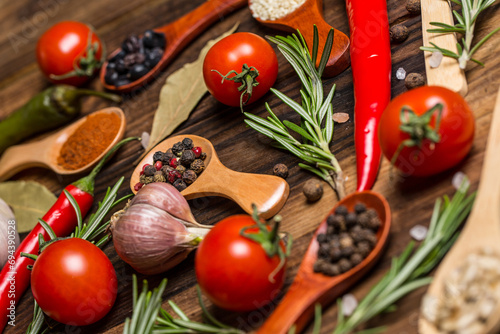 Many different spices and vegetables on a wooden table, aromatic spices and fresh vegetables for cooking, a variety of spices