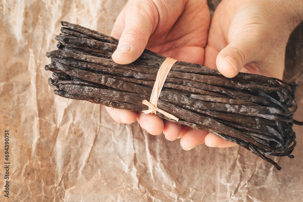 the world's best vanilla from Madagascar, premium quality, aromatic addition to cakes and desserts, a bunch of whole vanilla beans in paper, tasty and healthy organic additions in the kitchen - obrazy, fototapety, plakaty 