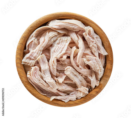 Boiled shredded chicken meat in a wooden bowl isolated on a white background.