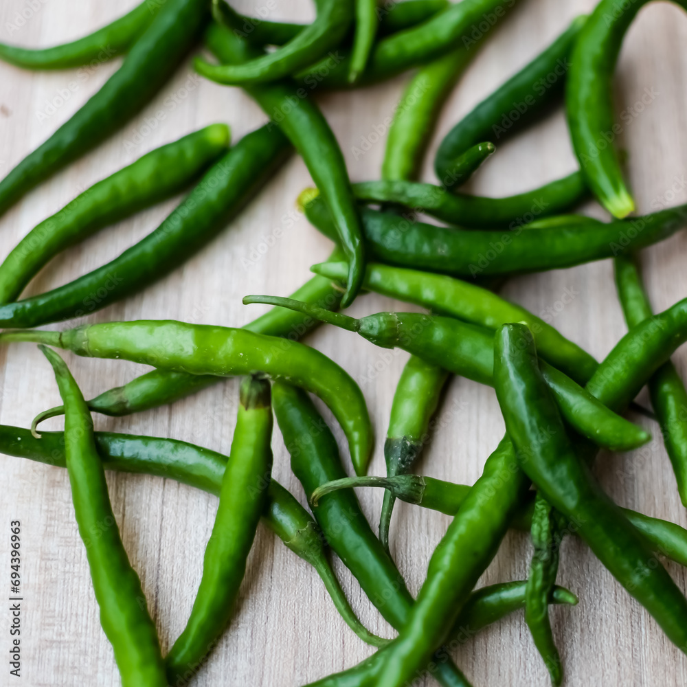 Fresh Green chili pepper on plain wooden table, green essential vegetables for all essential foods, view of unpeeled vegetables with plain background Fresh Green chili pepper on plain wooden table, green essential vegetables for all essential foods, view of unpeeled vegetables with plain background