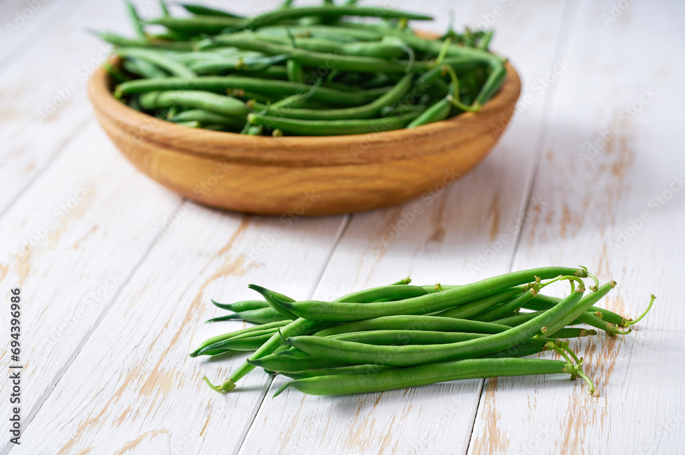 fresh green beans in a bowl on a wooden table, copy space for text. fresh green beans in a bowl on a wooden table, copy space for text.