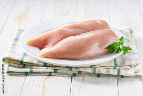 Bild auf Leinwand Raw chicken fillet with parsley in a plate on a wooden table.