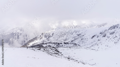 The white snowy peaks of Pirin covered with snow and fog. Snowy weather conditions for winter sports and tourism. Bansko Alpine Ski Resort, Bulgaria.