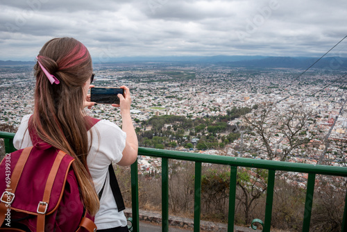 Mujer turista tomando fotos desde el mirador del Cerro San Bernardo, en la ciudad de Salta photo