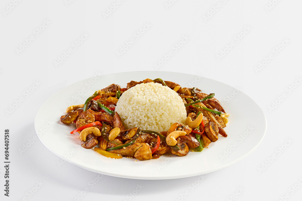Chicken Cashew dish served with white rice, closeup, on white
