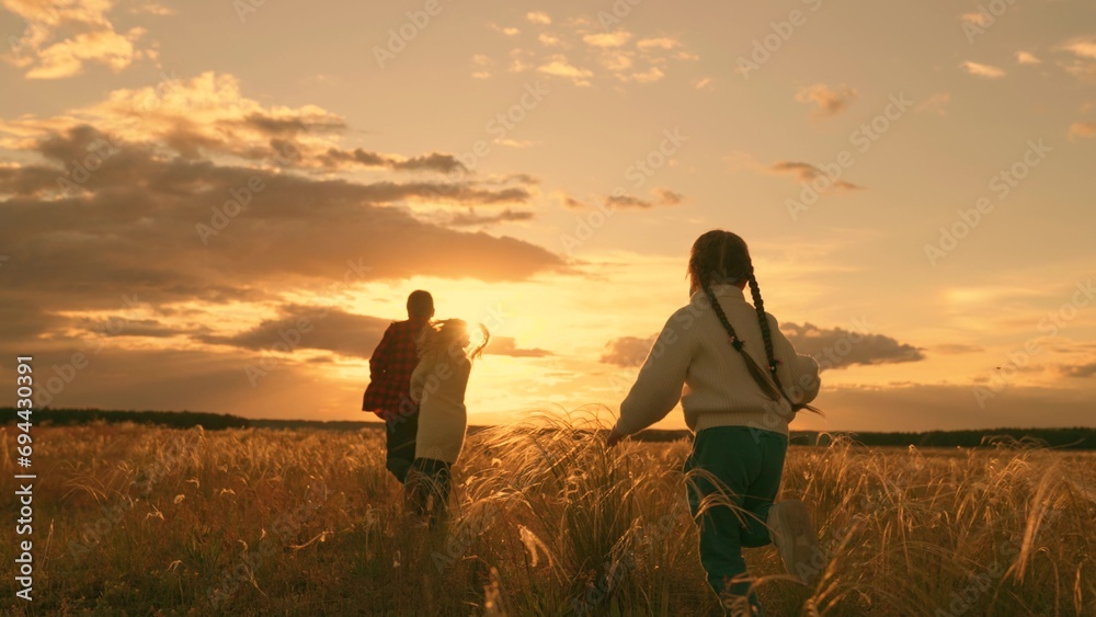Children run together in park at sunset on grass. Happy family, teamwork. Running children, boy, girl, dream of flying, raise your hands like an airplane. Children play in sun, flight, freedom, nature